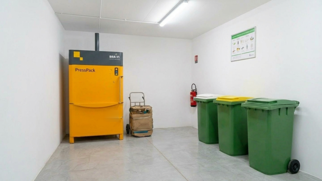 Presse à balles PressPack installée dans le local poubelles d'une copropriété résidentielle en Île-de-France — compactage du bac jaune −80%